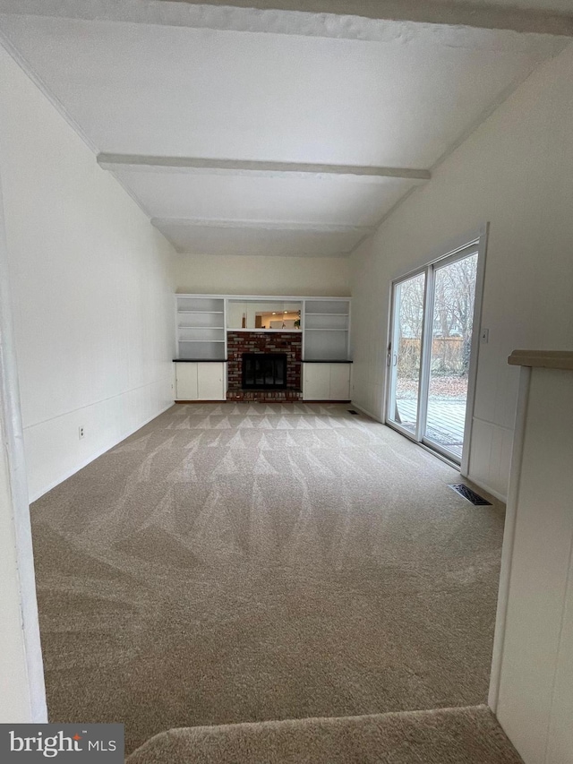 unfurnished living room with carpet, lofted ceiling with beams, and a fireplace