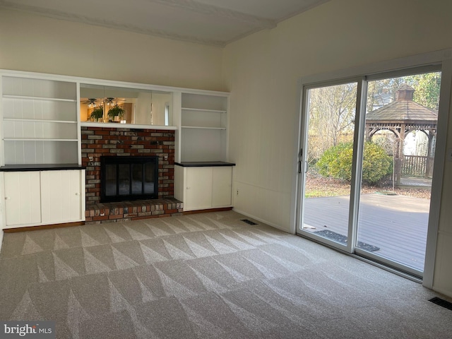 unfurnished living room featuring carpet and a brick fireplace