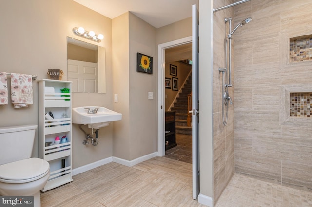 bathroom with sink, toilet, and tiled shower