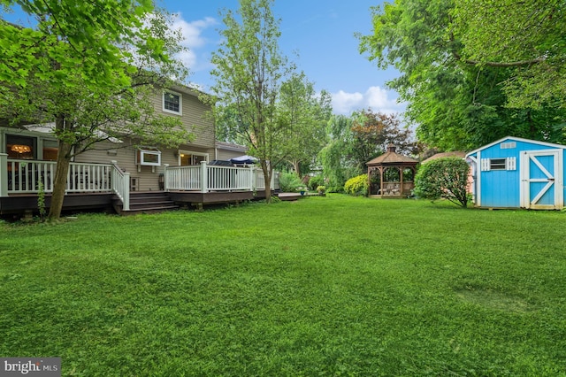 view of yard with a gazebo, a wooden deck, and a shed