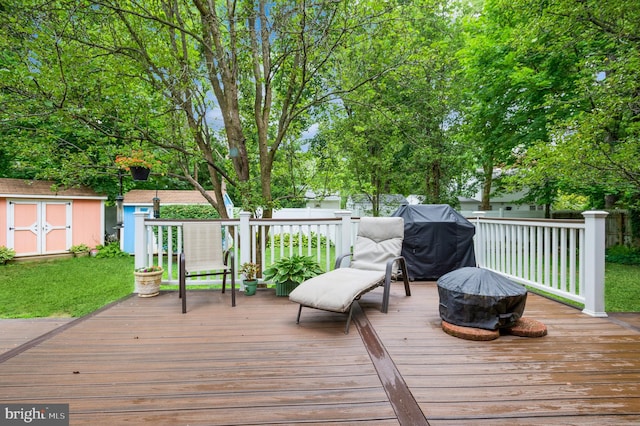 wooden terrace with a fire pit, a storage shed, and grilling area