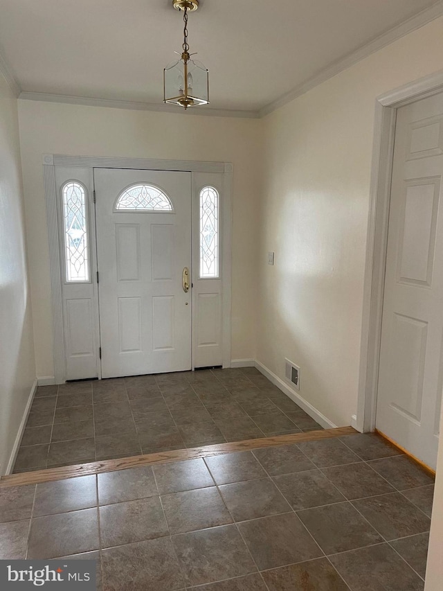 foyer featuring dark tile patterned flooring, an inviting chandelier, and ornamental molding