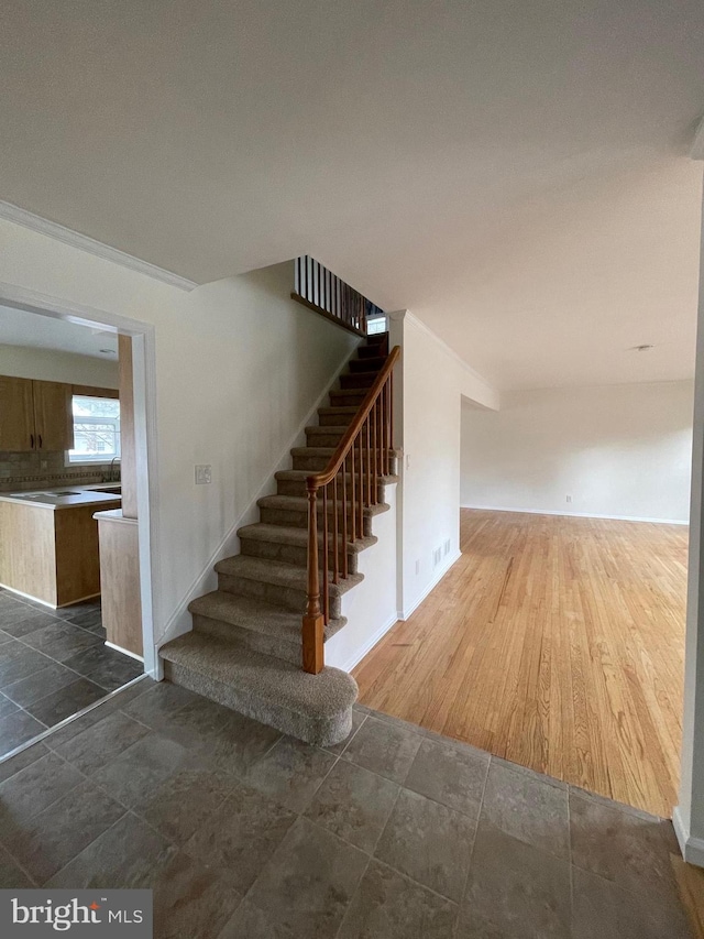 stairs featuring wood-type flooring and ornamental molding