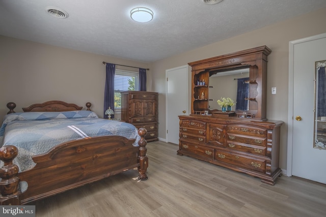 bedroom with a textured ceiling and light hardwood / wood-style flooring