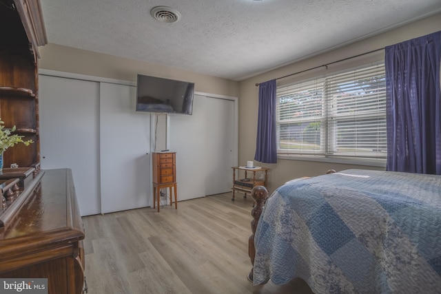 bedroom with light wood-type flooring and a textured ceiling