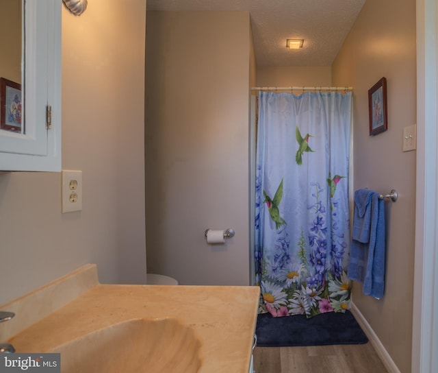 bathroom featuring hardwood / wood-style floors, a textured ceiling, toilet, vanity, and a shower with shower curtain