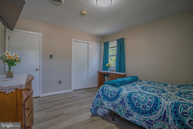 bedroom featuring a textured ceiling, light hardwood / wood-style floors, and a closet