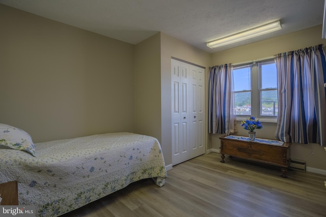 bedroom with a closet, hardwood / wood-style floors, and a textured ceiling