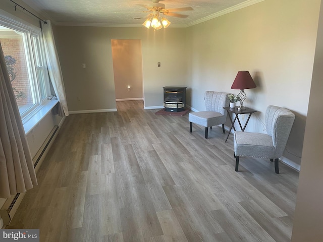 living area featuring crown molding, light hardwood / wood-style flooring, a wealth of natural light, and a baseboard radiator