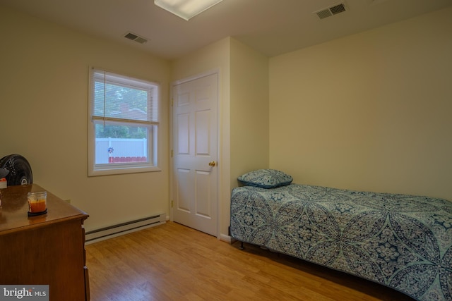 bedroom with baseboard heating and light hardwood / wood-style flooring