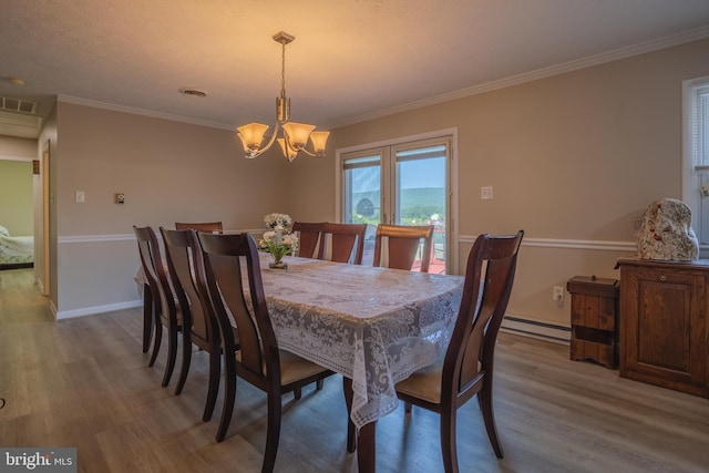 dining space with baseboard heating, hardwood / wood-style flooring, ornamental molding, and an inviting chandelier