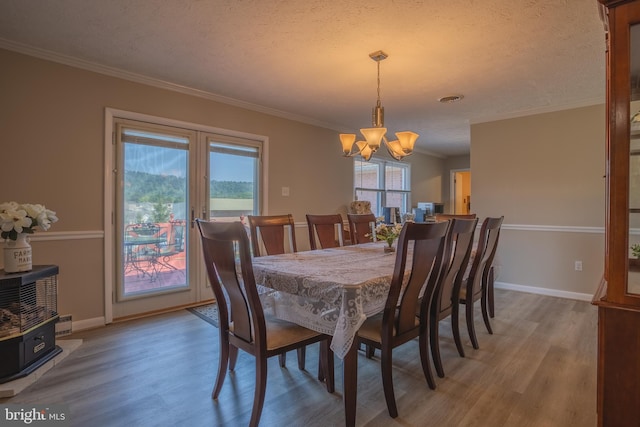 dining room featuring a textured ceiling, hardwood / wood-style flooring, crown molding, and a notable chandelier