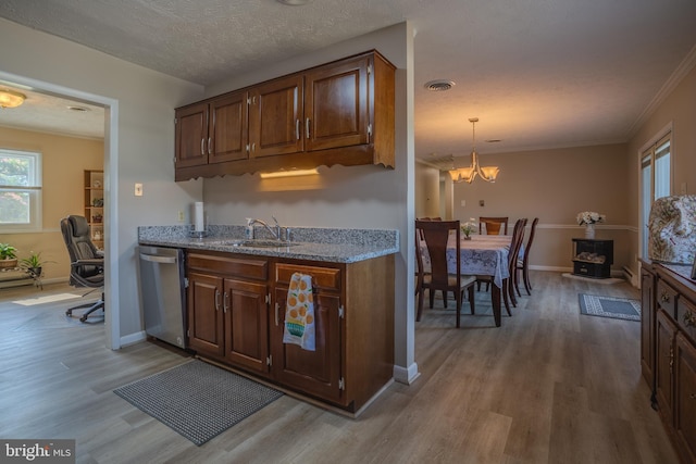 kitchen featuring stainless steel dishwasher, a textured ceiling, pendant lighting, a notable chandelier, and light hardwood / wood-style floors