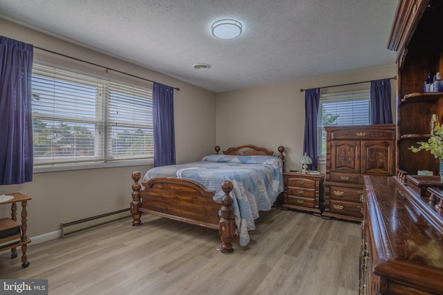 bedroom featuring a textured ceiling, light hardwood / wood-style floors, and a baseboard heating unit