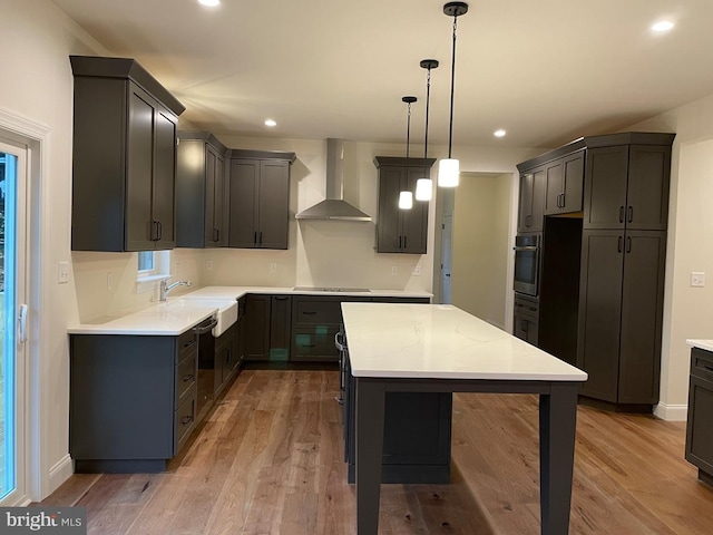 kitchen featuring wall chimney range hood, sink, decorative light fixtures, decorative backsplash, and white cabinetry