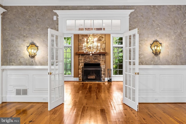 interior space with hardwood / wood-style floors, an inviting chandelier, a stone fireplace, and a wealth of natural light