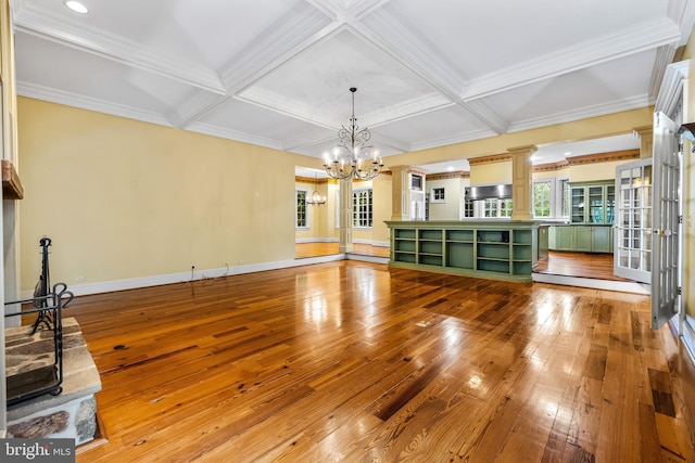 unfurnished living room featuring beam ceiling, coffered ceiling, crown molding, a chandelier, and light hardwood / wood-style floors