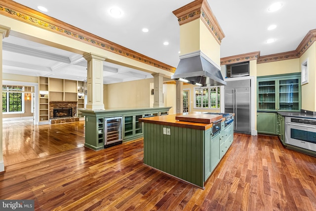 kitchen with wood counters, stainless steel appliances, beverage cooler, beam ceiling, and a kitchen island