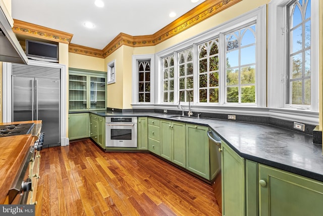 kitchen with wooden counters, sink, green cabinetry, dark hardwood / wood-style floors, and premium appliances