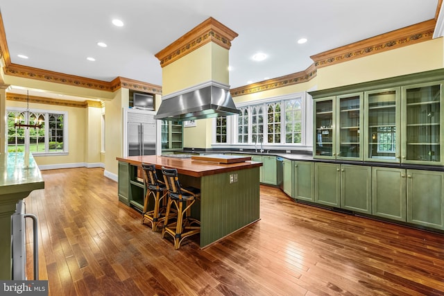 kitchen with pendant lighting, a center island, wooden counters, ornamental molding, and island range hood