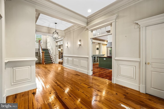 interior space featuring wood-type flooring, an inviting chandelier, and ornamental molding