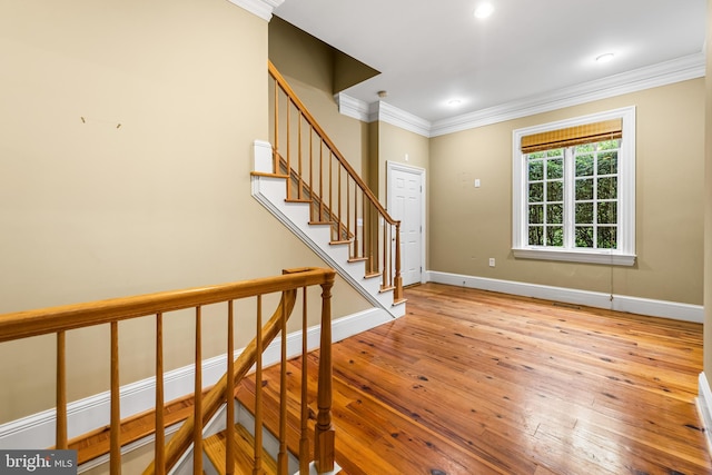 stairway with hardwood / wood-style flooring and crown molding