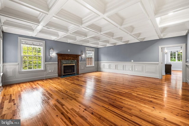 unfurnished living room with plenty of natural light, light hardwood / wood-style floors, beam ceiling, and a high end fireplace