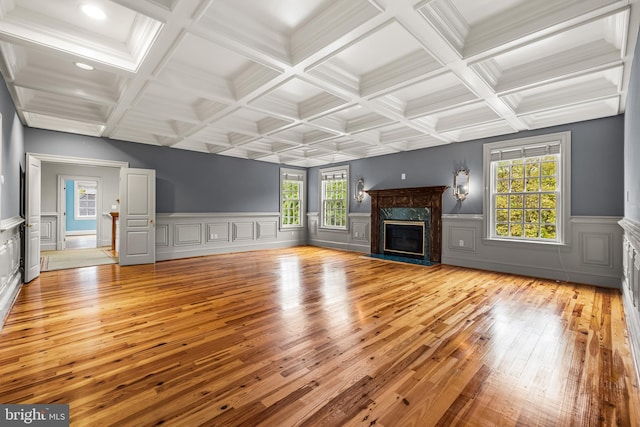 unfurnished living room with a high end fireplace, light wood-type flooring, and coffered ceiling