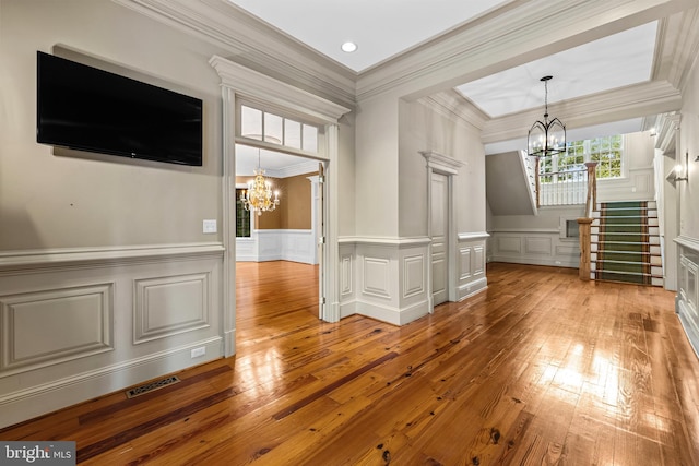 interior space featuring a notable chandelier, light hardwood / wood-style floors, and ornamental molding