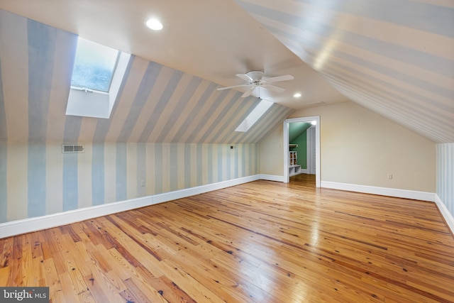 bonus room featuring light hardwood / wood-style floors, lofted ceiling with skylight, and ceiling fan