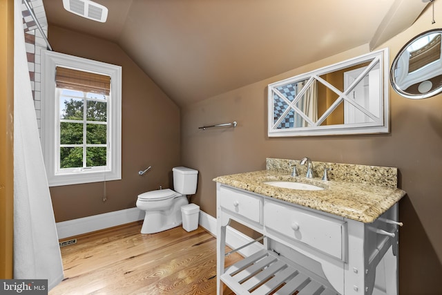 bathroom featuring toilet, hardwood / wood-style floors, vanity, and vaulted ceiling