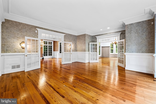 unfurnished living room featuring crown molding, french doors, and light wood-type flooring