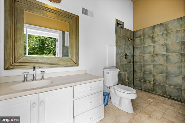 bathroom with a tile shower, vanity, and toilet