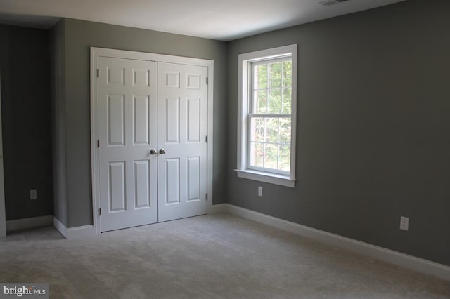 unfurnished bedroom with light carpet and a closet