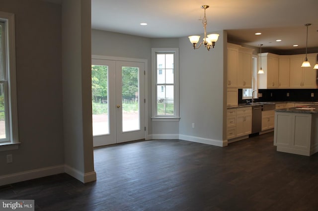 kitchen with french doors, dark hardwood / wood-style flooring, stainless steel dishwasher, an inviting chandelier, and hanging light fixtures