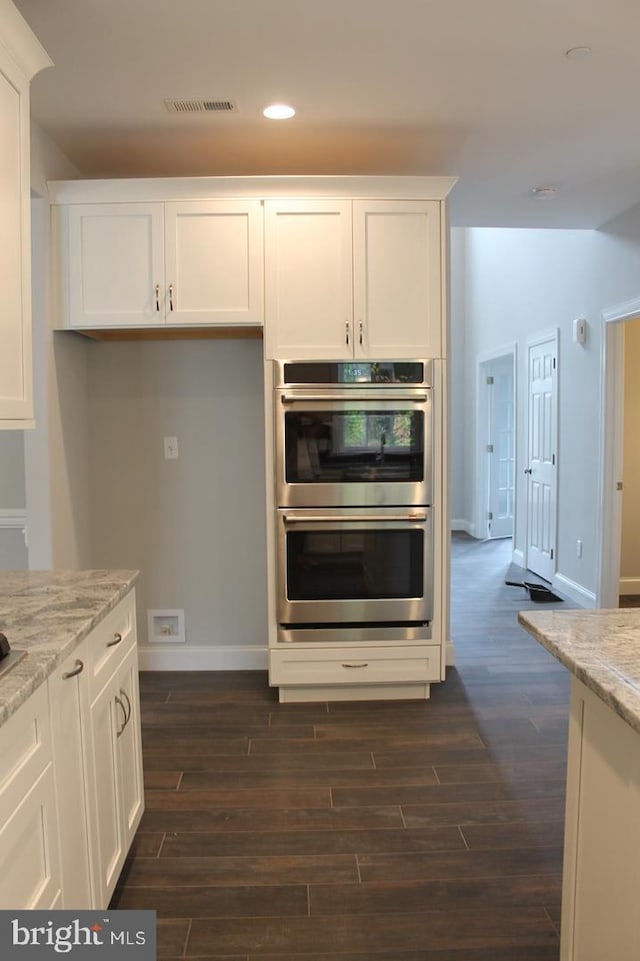 kitchen with white cabinets, stainless steel double oven, and light stone counters