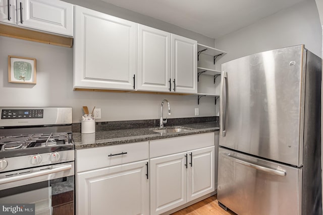 kitchen with sink, white cabinets, dark stone counters, and stainless steel appliances