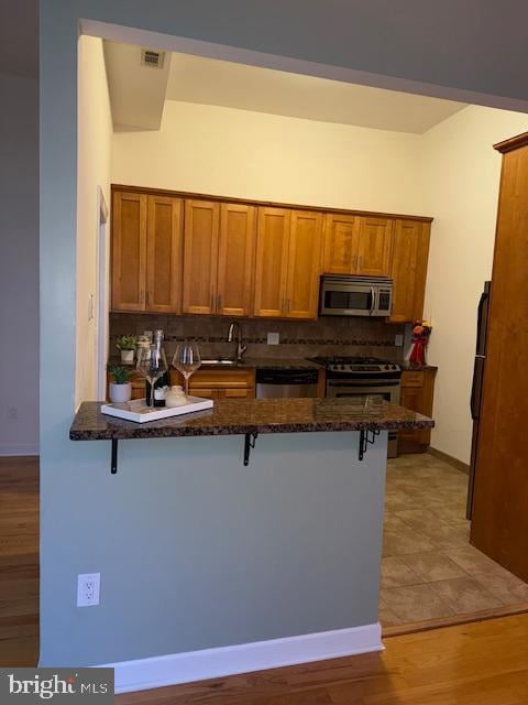 kitchen with appliances with stainless steel finishes, a breakfast bar area, and kitchen peninsula