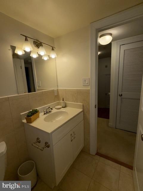 bathroom featuring vanity, toilet, tile patterned floors, and tile walls