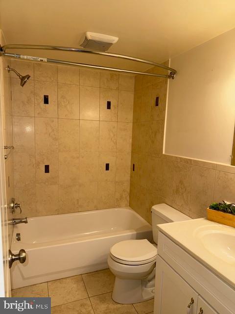 full bathroom featuring tile walls, toilet, vanity, tiled shower / bath combo, and tile patterned floors