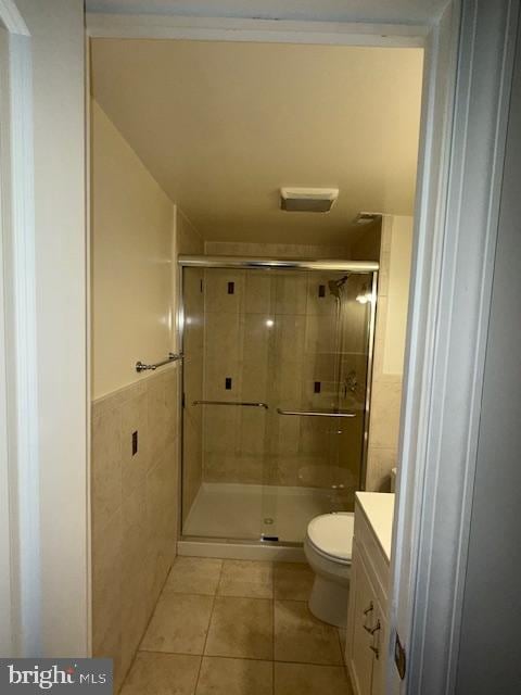 bathroom featuring toilet, walk in shower, vanity, and tile patterned floors