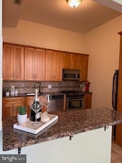 kitchen featuring dark stone countertops, range with electric stovetop, and kitchen peninsula