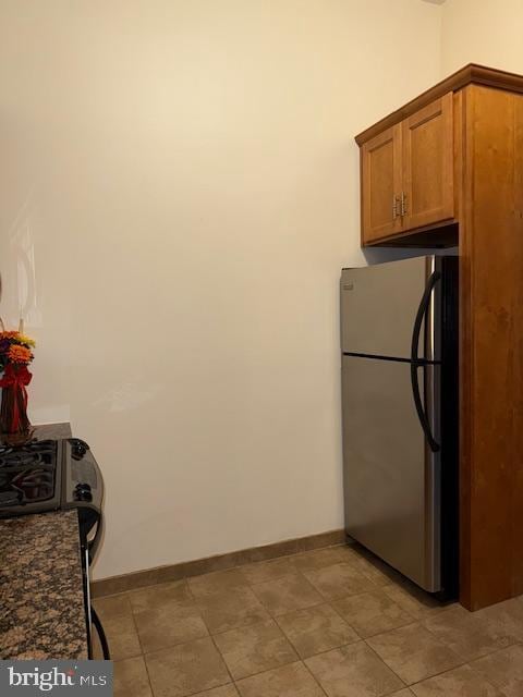 kitchen featuring dark stone counters and stainless steel refrigerator