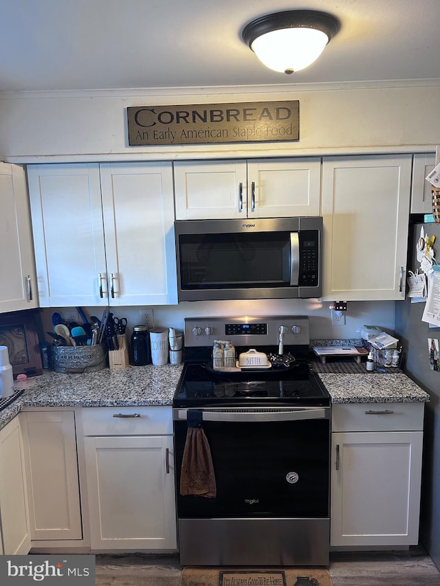 kitchen with white cabinetry, dark wood-type flooring, light stone countertops, stainless steel appliances, and crown molding