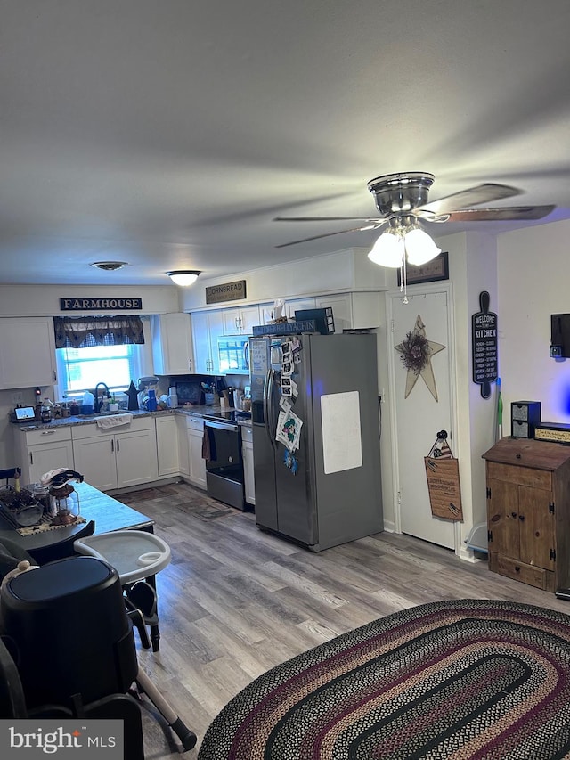 interior space with light hardwood / wood-style floors, white cabinetry, tasteful backsplash, stainless steel appliances, and ceiling fan