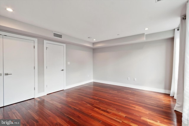 unfurnished bedroom featuring hardwood / wood-style floors and multiple closets