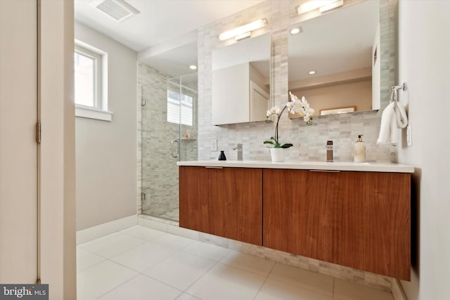 bathroom with dual vanity, backsplash, an enclosed shower, and tile patterned floors