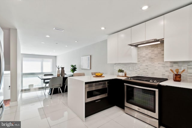 kitchen with decorative backsplash, stainless steel gas range oven, oven, white cabinets, and light tile patterned floors