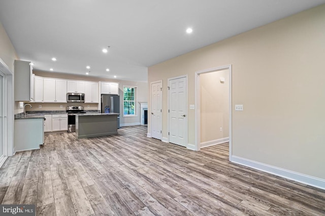 kitchen featuring appliances with stainless steel finishes, sink, white cabinetry, light hardwood / wood-style flooring, and a kitchen island