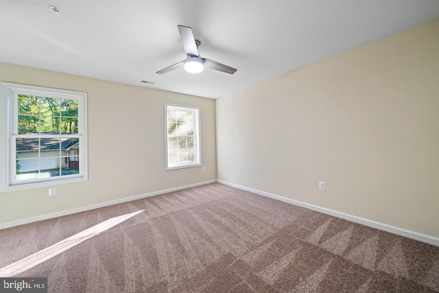 carpeted empty room with ceiling fan and a wealth of natural light